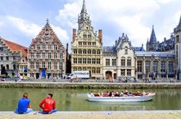two men sitting alongside a city canal in Belgium